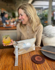 Woman sitting at a bar table with a shimmer beige and silver heart wristlet