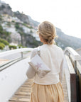 Woman standing on Italy coast with shimmer beige and star wristlet slung over shoulder