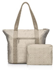 Woman traveling with a beige Signature travel tote and matching medium pouch.