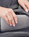 Close-up of hands sliding a laptop into the black signature backpack's rear padded sleeve.
