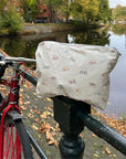 Medium white zipper pouch with colorful bicycles pattern sitting on next to a bicycle