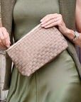 Woman in army green dress holding woven shimmer bronze zipper clutch