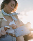 Woman holding a blue bandana wristlet with a heart design outdoors.