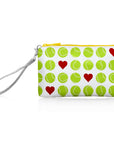 A small zip pouch with a wrist strap with green tennis balls and red hearts pattern and a yellow zipper.