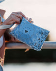 Person holding a blue bandana patterned wristlet with a heart design.