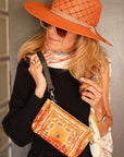 Woman wearing an orange hat and holding a matching orange handbag.