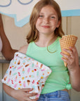 Smiling young girl holding an ice cream cone and an ice cream cone patterned zipper pouch