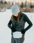 Woman in snow wearing Puffer Crossbody Fanny Pack Belt Bag in Silver with Black Strap