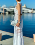 Woman carrying a silver stripe pouch used as a fold over clutch by the water.