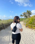 Woman on beach wearing Puffer Crossbody Fanny Pack Belt Bag in Shimmer Black
