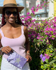 Woman in purple top holding purple pouch with star by flowers