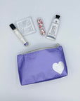 mini pouch in purple with silver heart with lip balm, hand lotion, perfume on white background