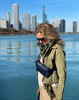 Woman overlooking Chicago skyline wearing Puffer Crossbody Fanny Pack Belt Bag in Shimmer Navy Blue