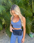 Woman in workout set wearing Puffer Crossbody Fanny Pack Belt Bag in Shimmer Navy Blue