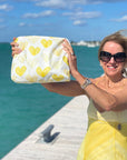 Woman wearing yellow dress holing yellow bag by water