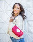 Smiling woman holding a crimson red with silver heart wristlet