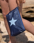 girl holding a mini zipper pouch that is navy blue with a light blue star that has water droplets on it.