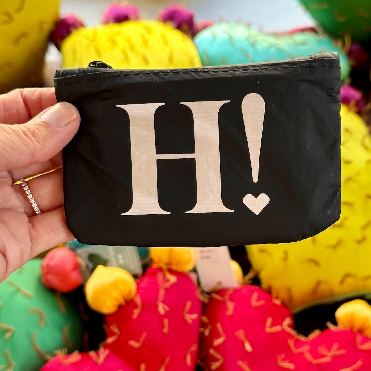 Black card pouch with silver H! against colorful background