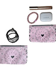 Little zipper pouches in a pink heart pattern Bandana Print storing lip gloss, hair tie, bracelets and ear pods on a white background.