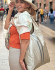 Woman holding a large beige tote bag on a city street