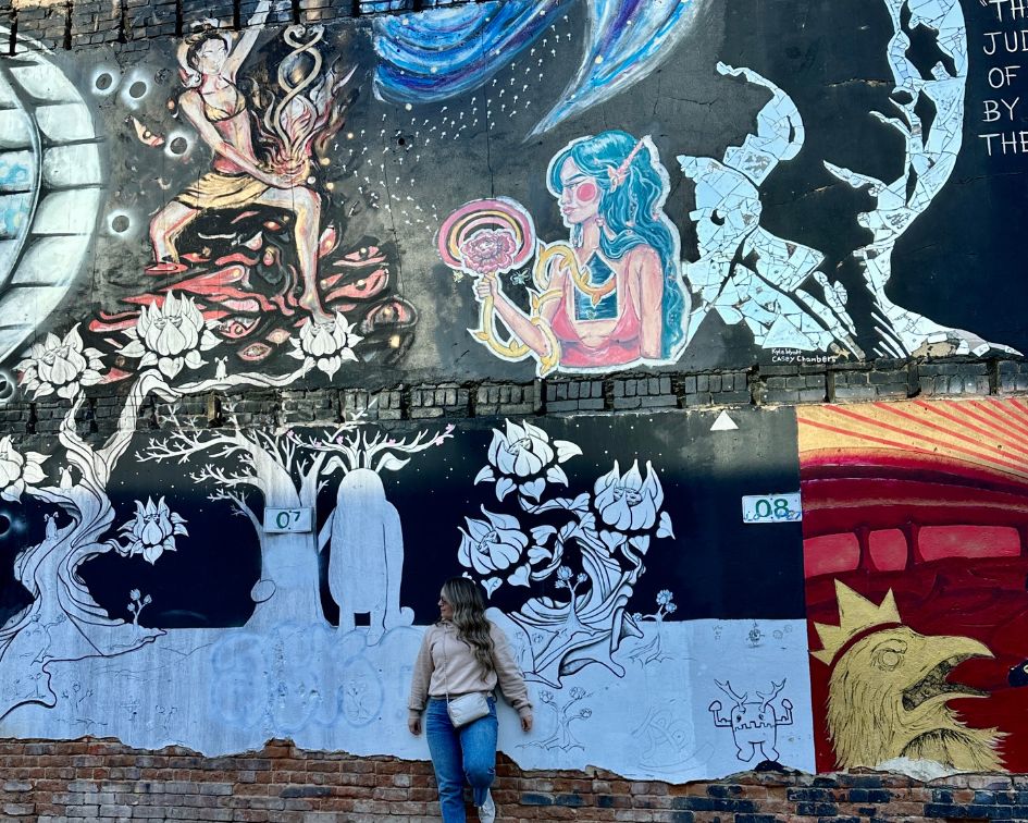 Woman standing against mural wearing mini puffer chain purse in Boise, Idaho