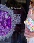 Woman holding a colorful gemstone print bag next to a purple gemstone ring with 'Gemstone Dreams' text.