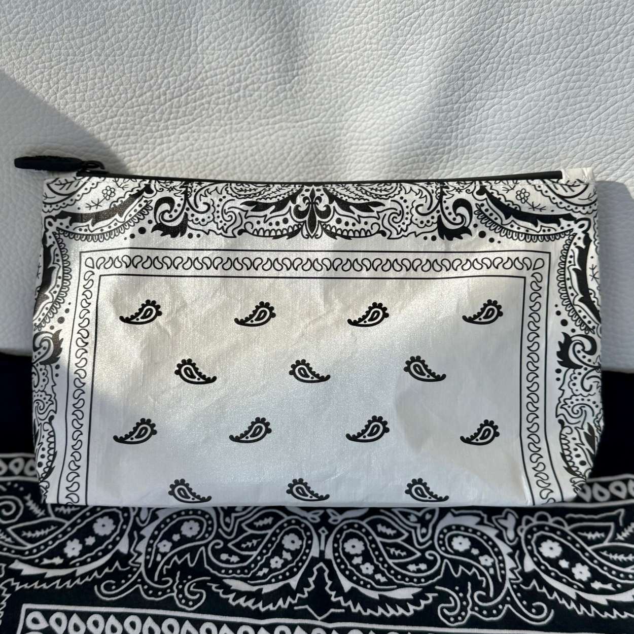 Cosmetic zipper pouch in shimmer white bandana print on black bandana and white leather background