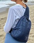 Person on beach with crossbody backpack in shimmer navy with tonal star