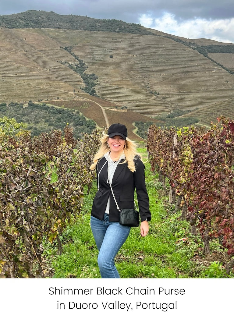 Woman standing in Duoro Valley, Portugal carrying black crossbody chain purse