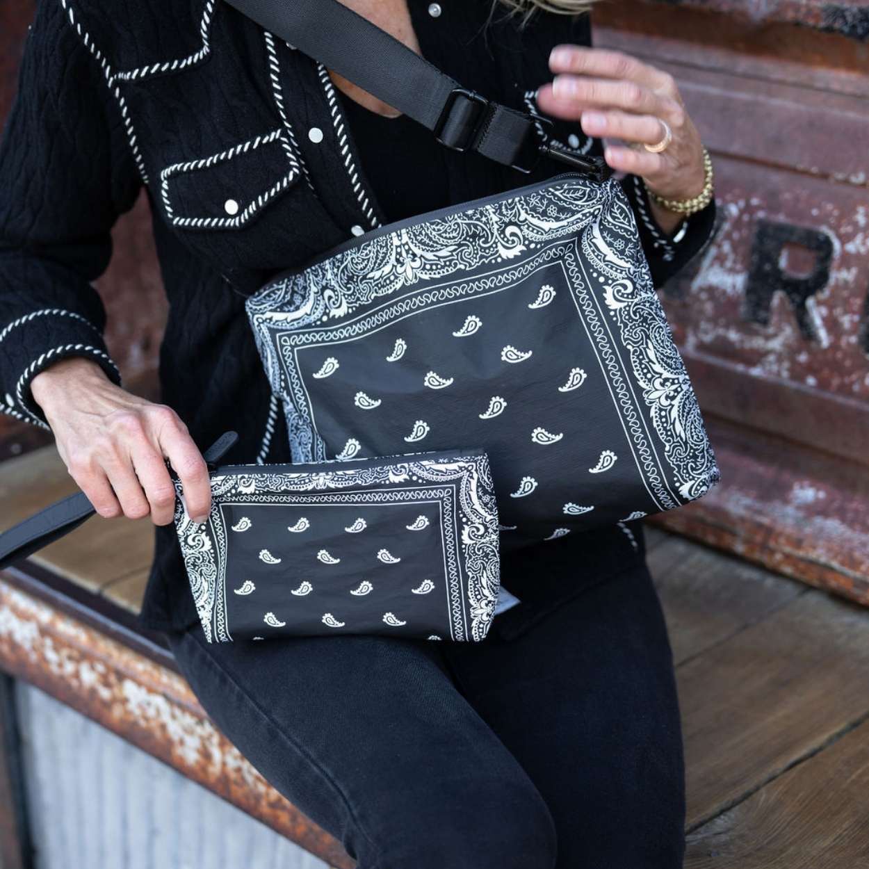 Women holding crossbody purse and mini zipper pouch in black bandana print