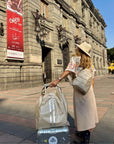 Woman with a suitcase and crossbody Backpack Sling bag in front of a museum