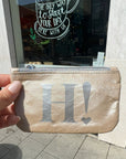 Shimmer beige emergency pouch held up in front of coffee shop