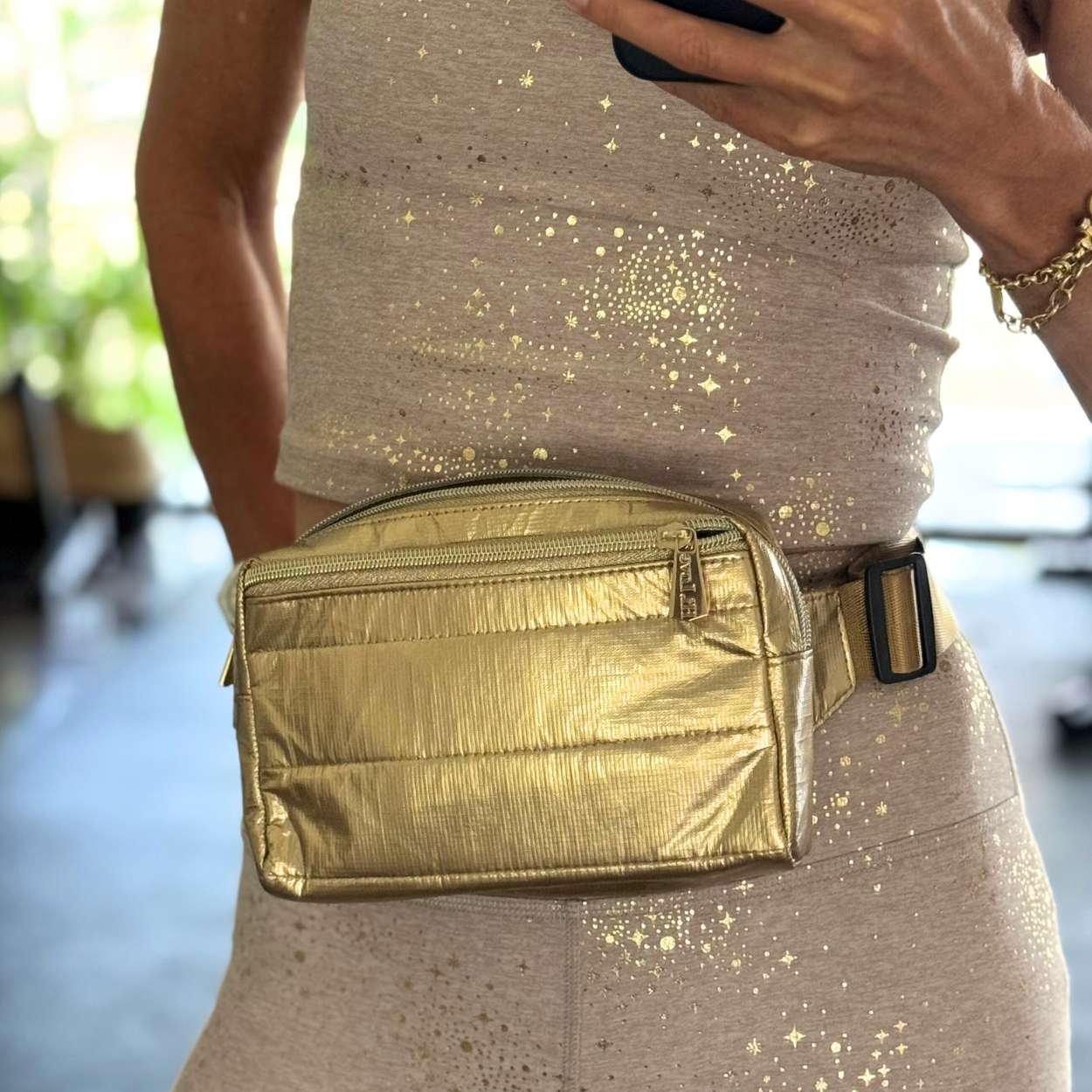 Woman in a workout outfit wearing a gold belt bag
