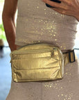 Woman in a workout outfit wearing a gold belt bag
