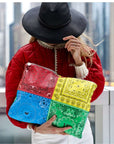 Person holding a colorful patchwork bandana clutch with a cityscape background