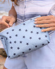 women holding a light blue with navy stars pouch unzipping it.