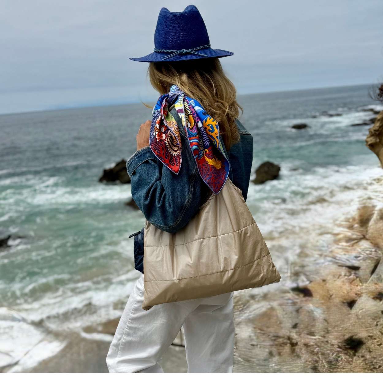 Women wearing beige tote bag with blue jean jacket near coastal waters