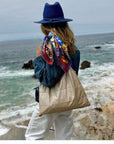 Women wearing beige tote bag with blue jean jacket near coastal waters