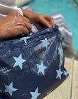 Person sitting by pool unzipping medium zipper pouch in shimmer navy with multi light blue stars