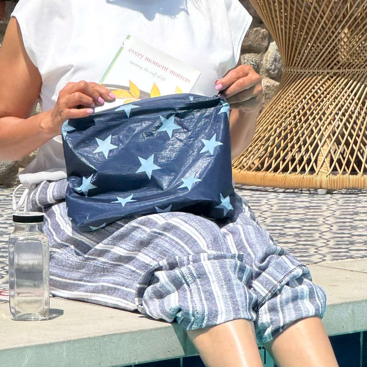 Person sitting by pool holding medium zipper pouch in shimmer navy with light blue stars