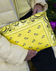 Person in yellow jacket holding medium zipper pouch in yellow bandana print