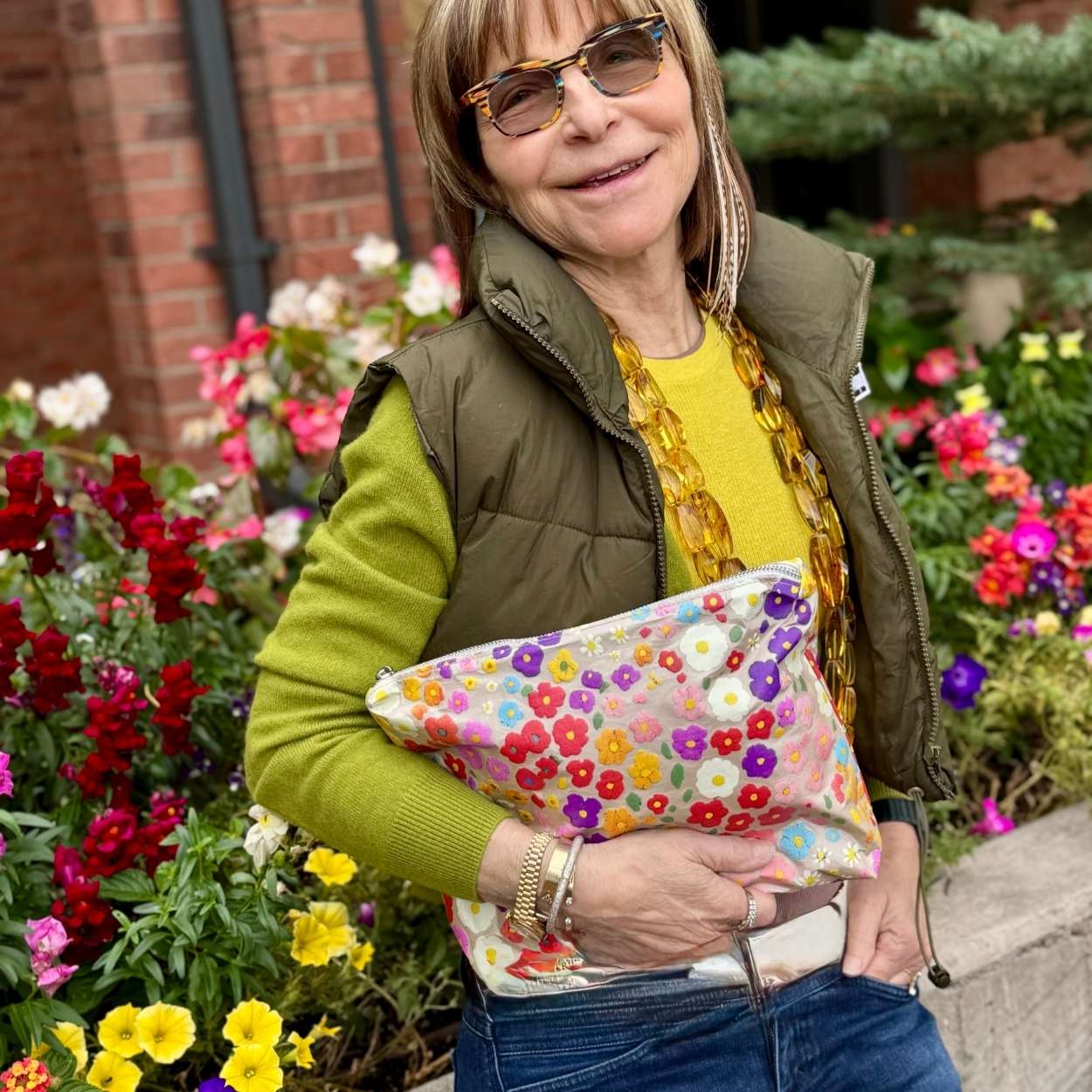 Woman in green sweater and vest near flowers holding medium zipper pouch in watercolor poppies pattern