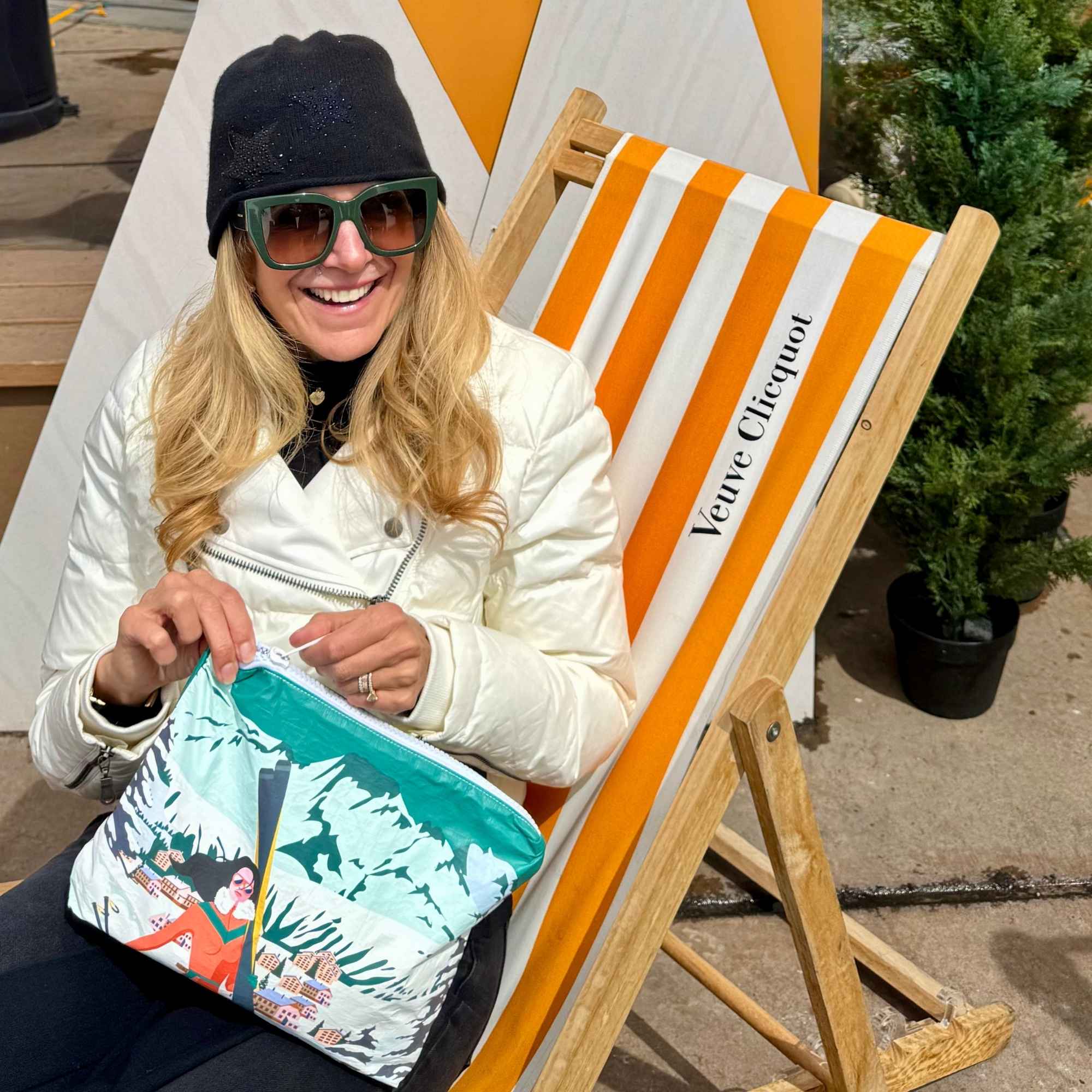 Woman enjoying Apres Ski with Clutch that has woman carrying skis to Chalet Scene printed on it