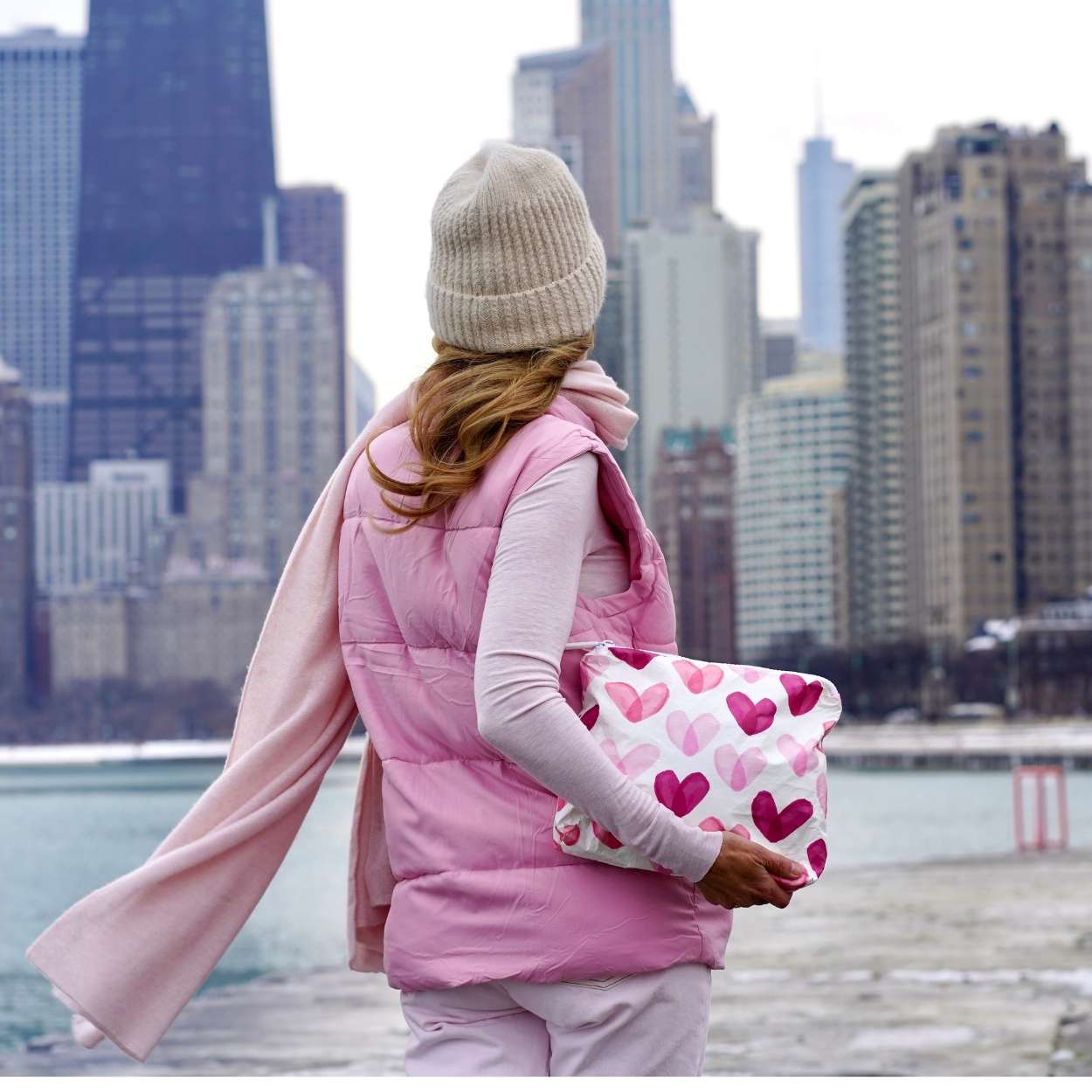 Woman carrying clutch with pink heart print in the city.