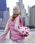 Woman carrying clutch with pink heart print in the city.