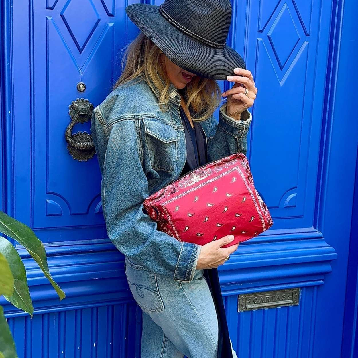 Person holding a red clutch in front of a blue door