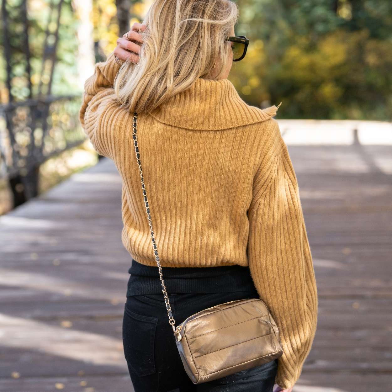 Person walking outdoors wearing mini puffer chain purse in shimmer bronze