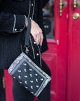 Person holding mini zipper pouch in black bandana print by red door