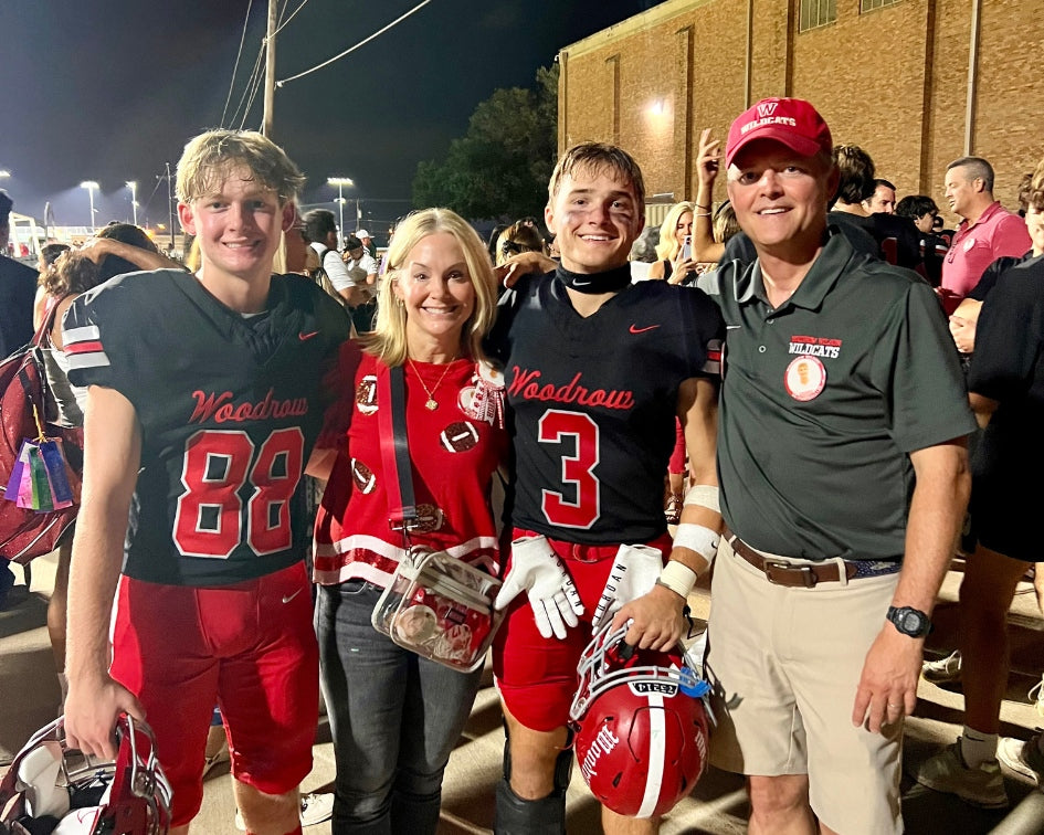 Family posing with football players and coach at a sports event