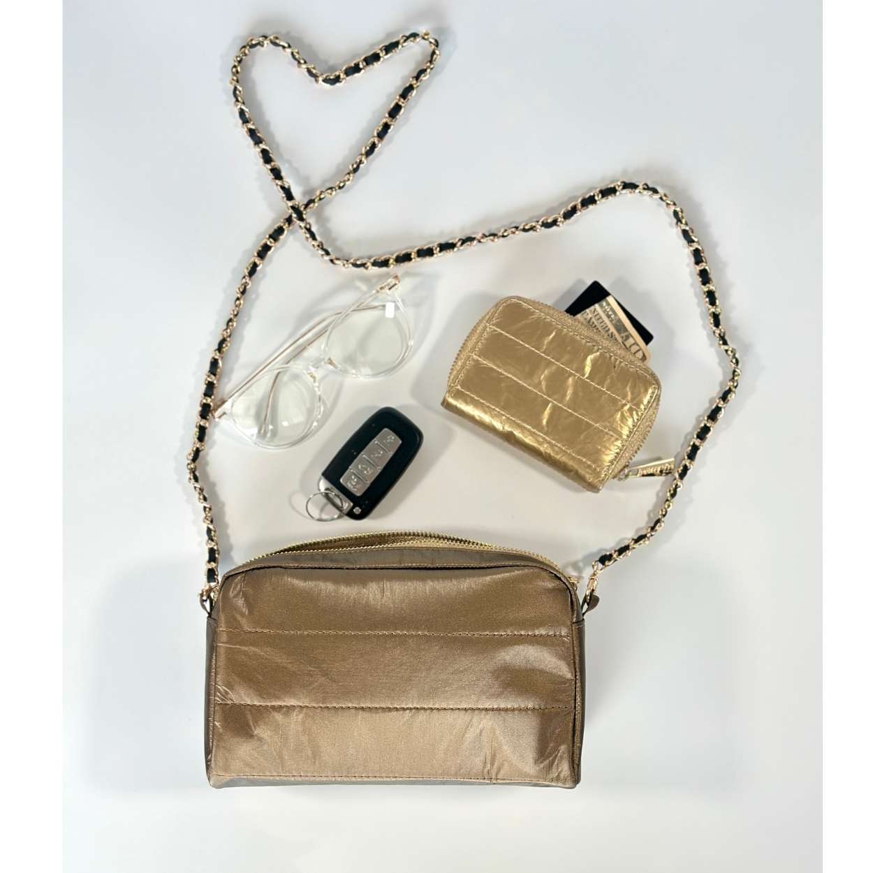 Bronze handbag with gold chain metal purse strap with reading glasses, gold wallet and keys on a white background